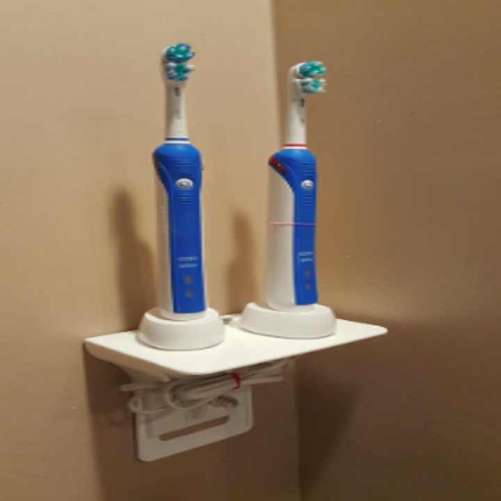 reviewer pic of outlet shelf with two electric toothbrushes stored on the shelf