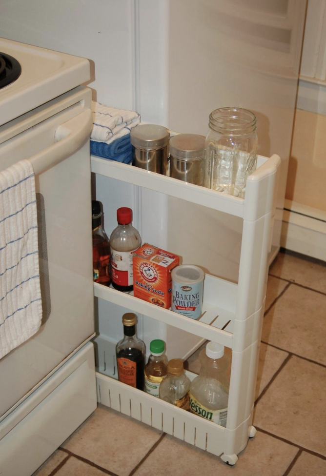 Reviewer pic of the three-tier skinny storage tower with assorted kitchen products in between a stove and fridge