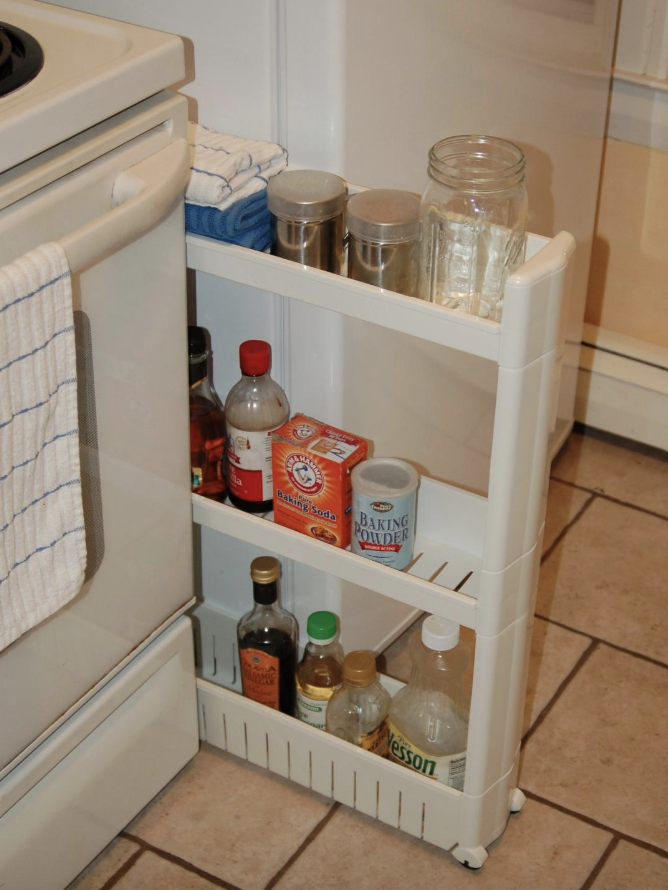 Reviewer pic of the three-tier skinny storage tower with assorted kitchen products in between a stove and fridge
