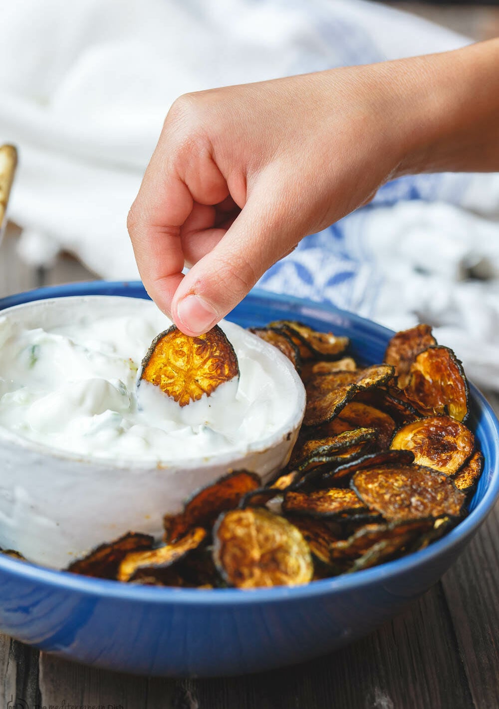 Crispy baked zucchini chips with dip in a bowl