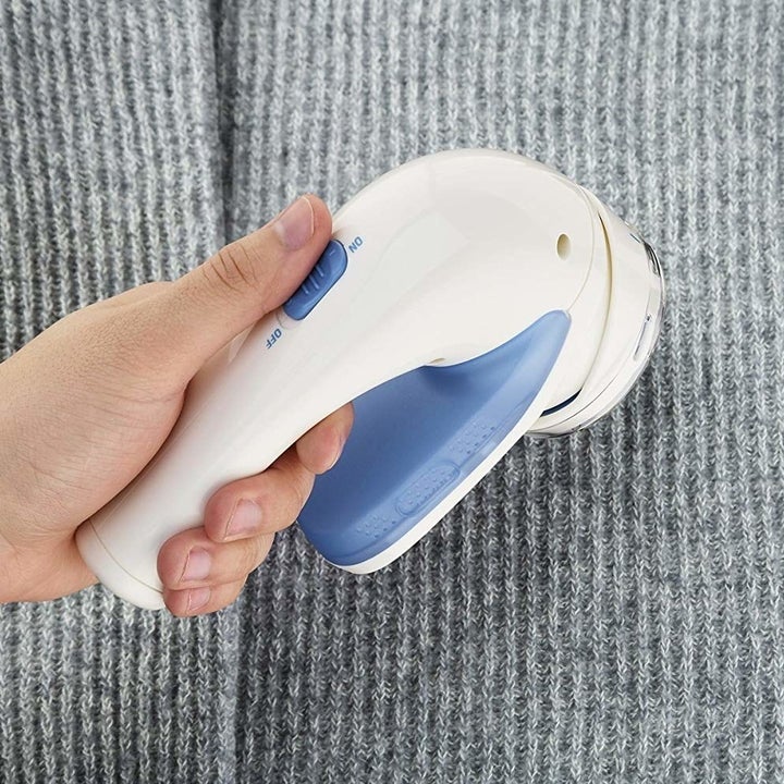 a hand using the fabric shaver