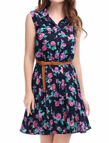 models wears navy dress with pink flowers and brown belt