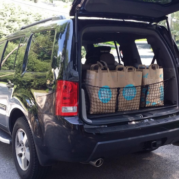 Reviewer photo of a trunk with groceries inside utilizing the mesh organizer