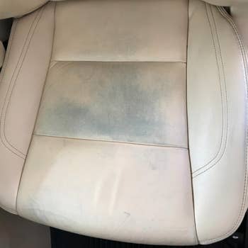 Reviewer photo of their beige leather car seats, which have dye stains transferred from their jeans