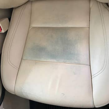 Reviewer photo of their beige leather car seats, which have dye stains transferred from their jeans