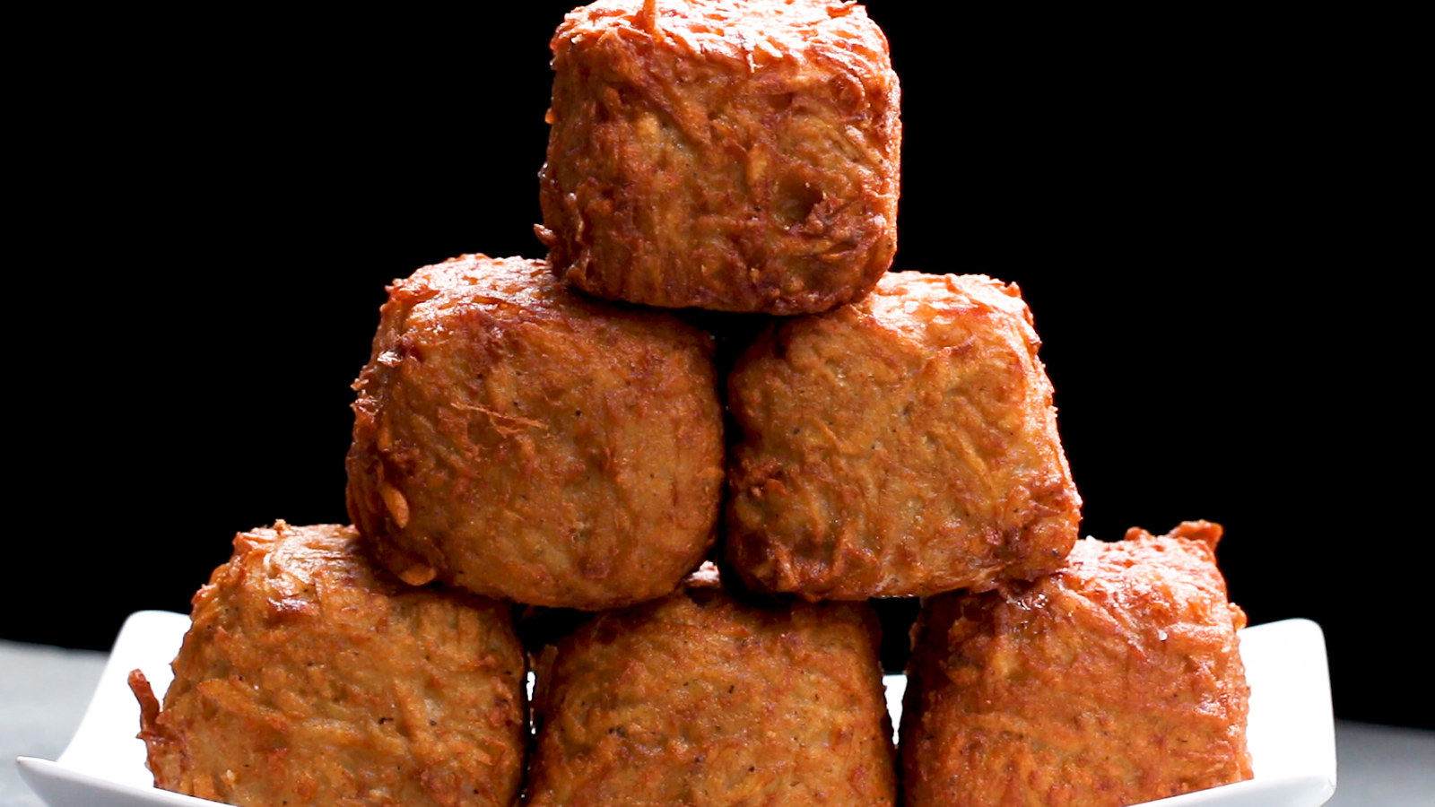 Rendimento: 4 Você vai precisar de:15 fatias de queijo cheddar15 fatias de presunto6 batatas médias ou 3 grandes1 ½ colheres de chá de sal½ colher de chá de pimenta¼ de xícara de farinha de trigo (30g)1 ovoÓleo para fritarModo de preparo:1. Em uma tábua de corte, coloque uma fatia do queijo cheddar e coloque uma do presunto por cima. Caso o presunto não for quadrado, corte-o para ficar do mesmo tamanho da fatia do queijo. Misture os retalhos do presunto com a cebola, a pimenta e o ovo. Corte o presunto e o queijo em 4 quadrados iguais. Repita com o restante do presunto e do queijo.2. Empilhe o presunto e o queijo até ter 10 camadas de presunto e 10 de queijo.3. Em uma tábua de corte, descasque as batatas. Rale as batatas em uma tigela grande forrada com um pano de prato.4. Assim que todas as batatas forem raladas, enrole a toalha firmemente e torça-a, espremendo toda a água das batatas. Descarte a água das batatas.5. Coloque as batatas raladas em uma tigela limpa e acrescente 1 colher de chá de sal, pimenta, farinha e o ovo. Misture bem.6. Envolva o cubo de presunto e queijo com a mistura de batata. Achate cada lado para criar um cubo. Repita com o resto dos cubos.7. Em uma assadeira forrada com papel-manteiga, coloque os cubos de batata suíça. Leve ao congelador por 2-3 horas ou até ficarem sólidos.8. Aqueça 10 cm de óleo em uma panela grande até a temperatura chegar aos 180ºC.9. Frite cada cubo por 4 minutos até dourar. Coloque-os sobre uma grade de esfriamento ou deixe-os secar sobre toalhas de papel. Deixe esfriar por 5 minutos. Polvilhe com o resto do sal.10. Sirva imediatamente e bom apetite!