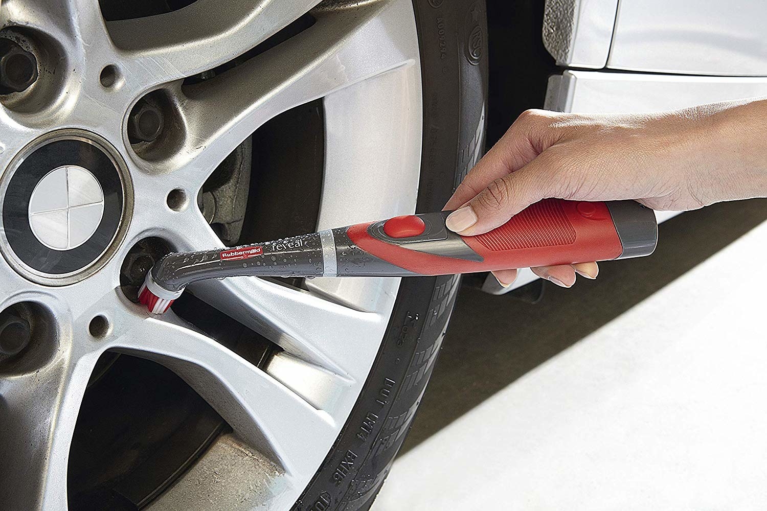 a model using the handheld brush tool to clean the wheels of their car