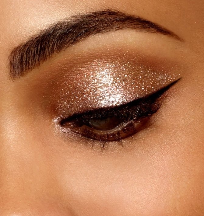 An eye with sparkly gold eyeshadow and sharp cat eye liner