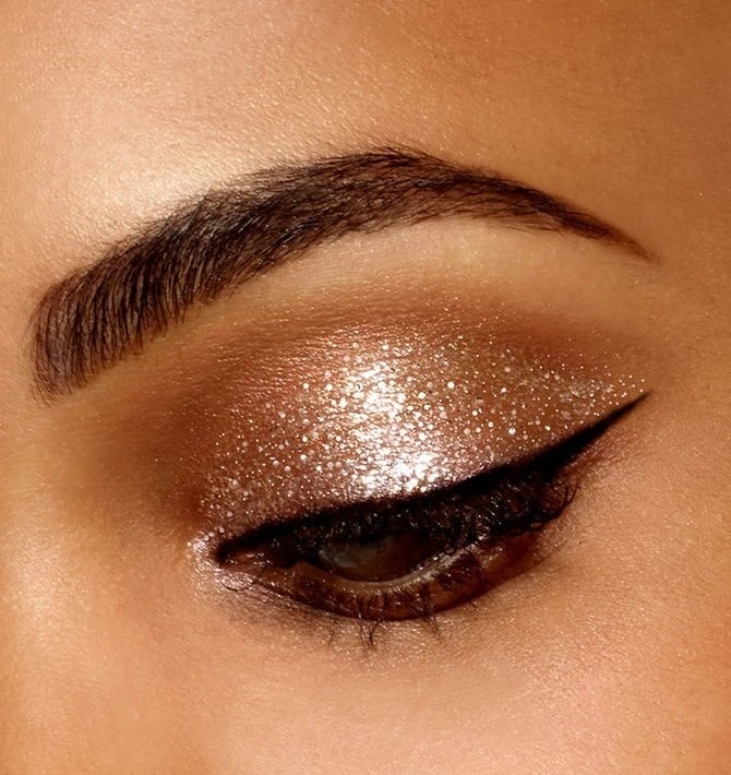 An eye with sparkly gold eyeshadow and sharp cat eye liner