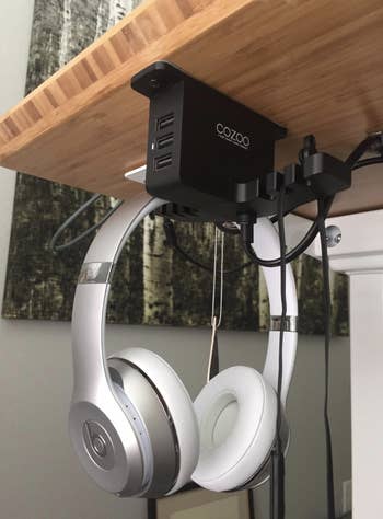 a reviewer using the under desk organizer to hang their head phones