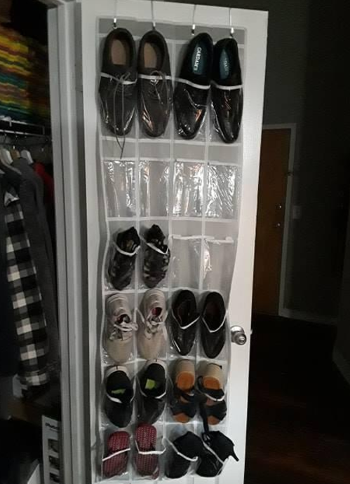 reviewer photo of shoes in organizer with clear pockets hanging on back of closet door 
