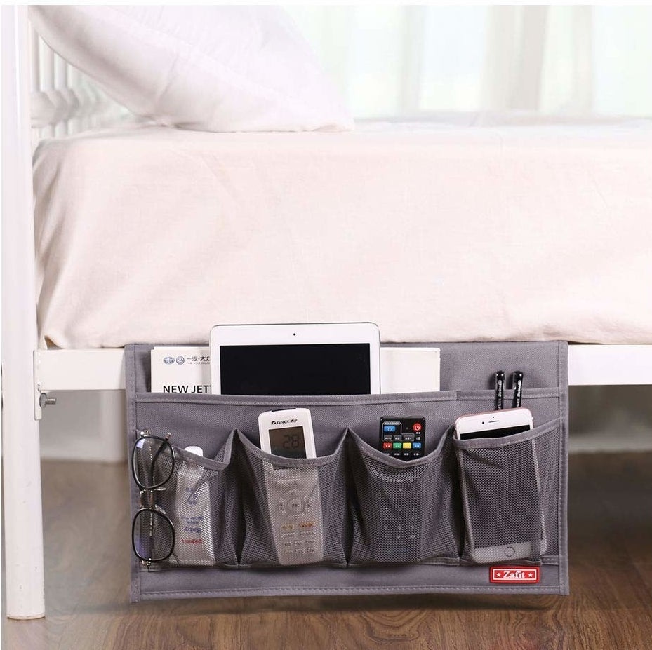 The caddy holding glasses, electronics, and remotes on the side of a bed