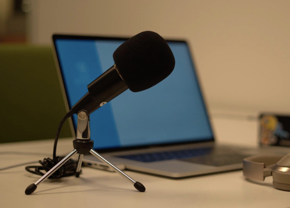 a black microphone propped up next to a laptop on a desk