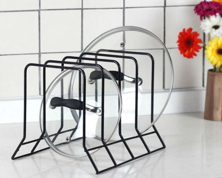 two pot lids stored in the bakeware holder on a kitchen counter