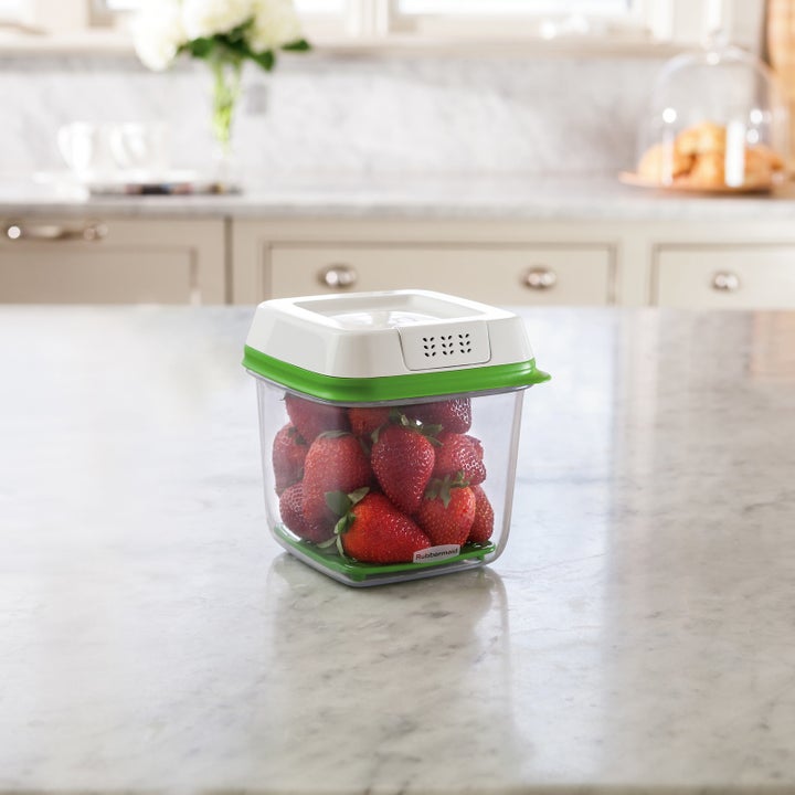 The rectangular plastic container with strawberries in it sitting on a counter