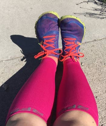 runner's legs with hot pink compression sleeves from their ankles to below their knees