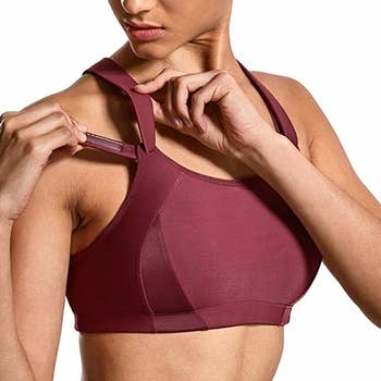 model adjusts strap of red high-impact sports bra