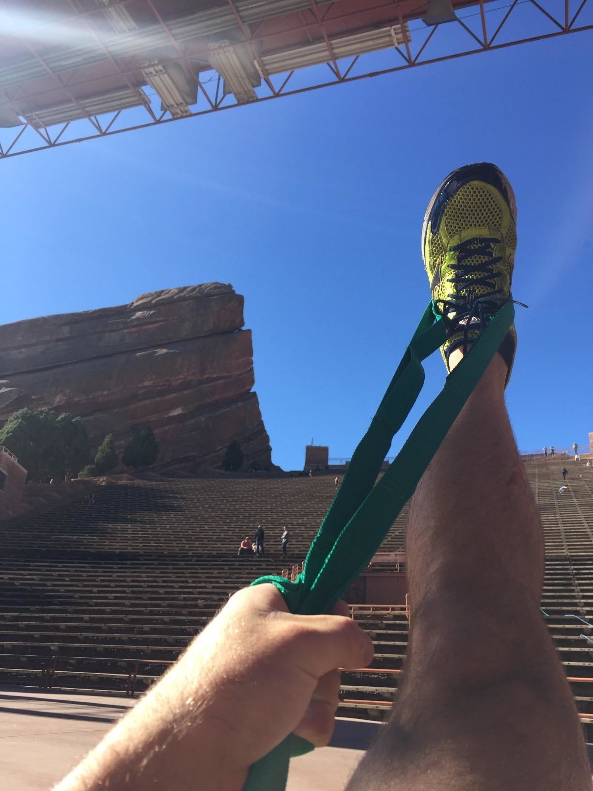 person stretching their right leg by gripping a green fabric strap around their foot