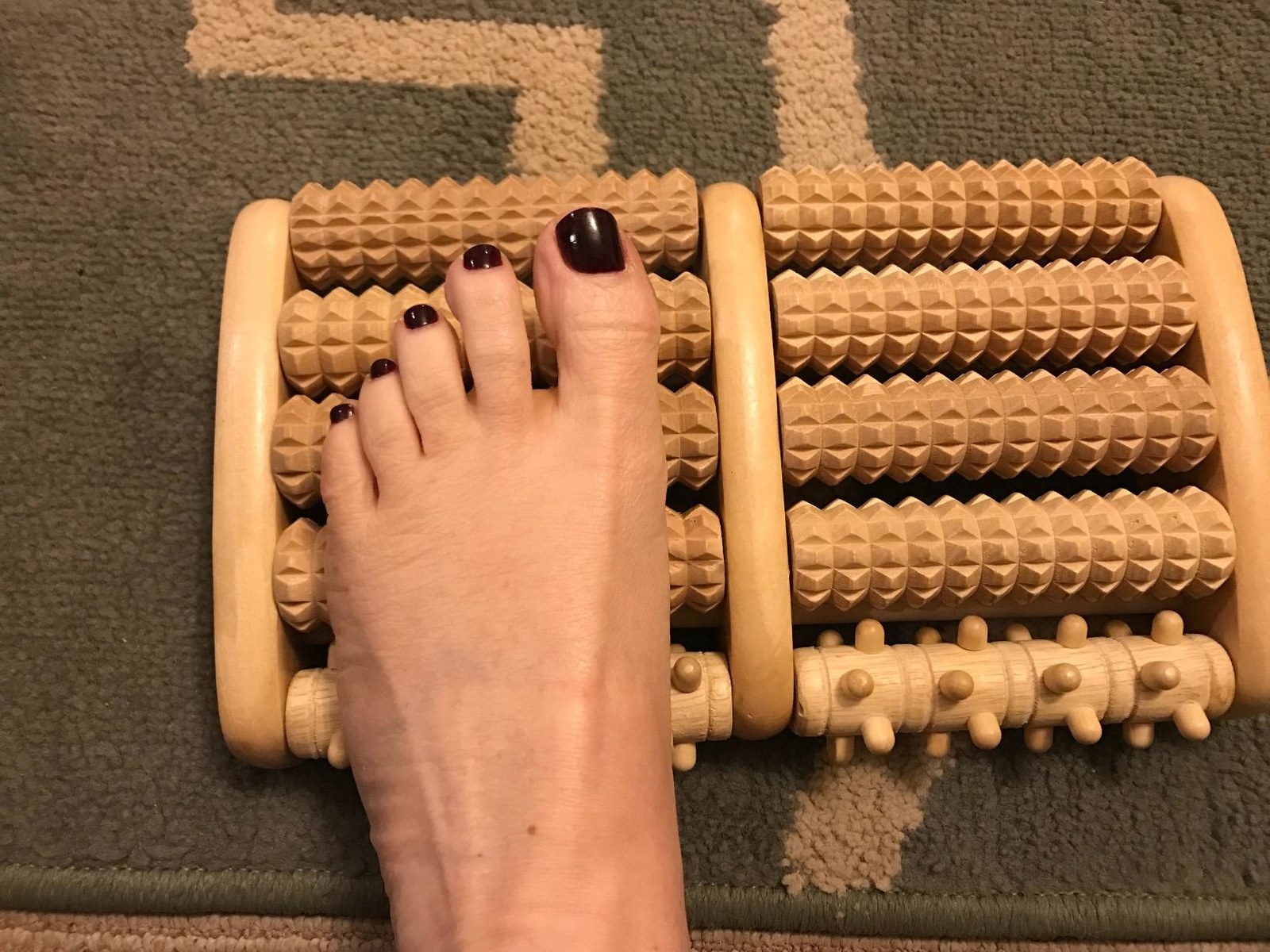 person&#x27;s foot on the wooden massager&#x27;s bumpy rollers