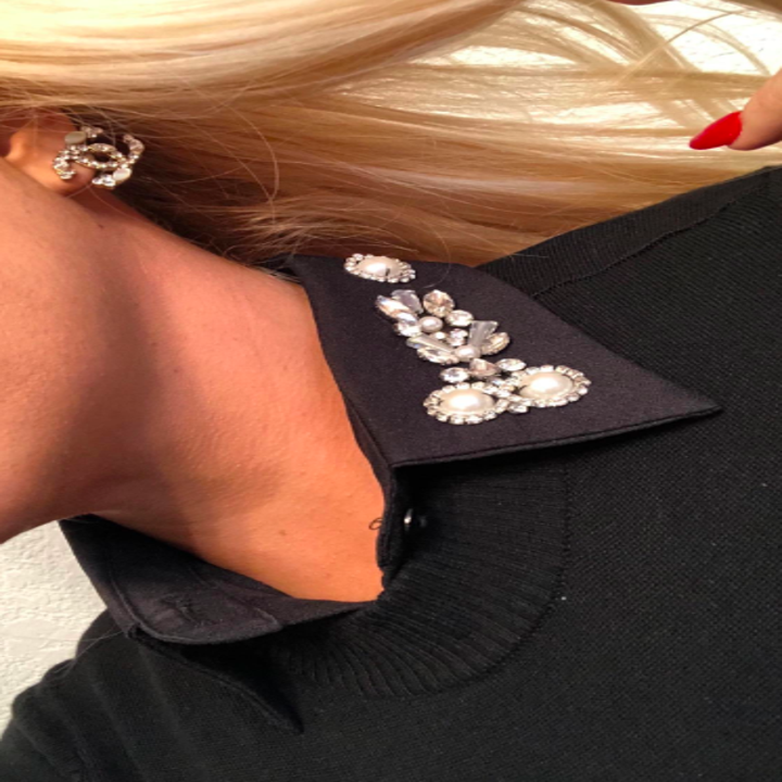 reviewer wears sweater with black collar with pearl-like stones and rhinestones 