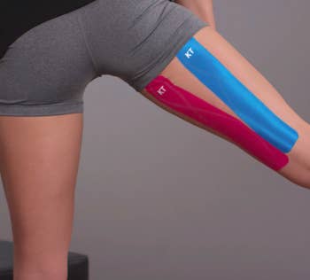 person wearing the tape in red and blue underneath their thigh for support