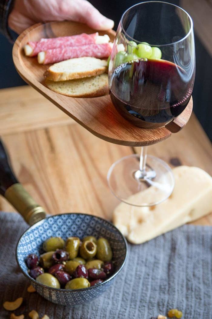 Wooden plate with built-in slot with wine glass hanging from it 