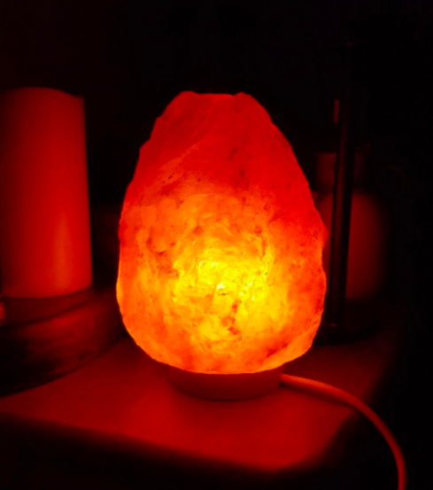 a reviewer&#x27;s photo of the salt lamp glowing on their nightstand