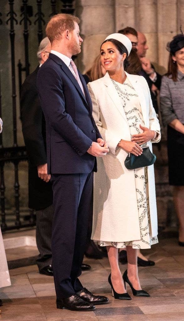 Meghan looks up at Harry with her hand on her belly as the two are royally dressed for the occasion