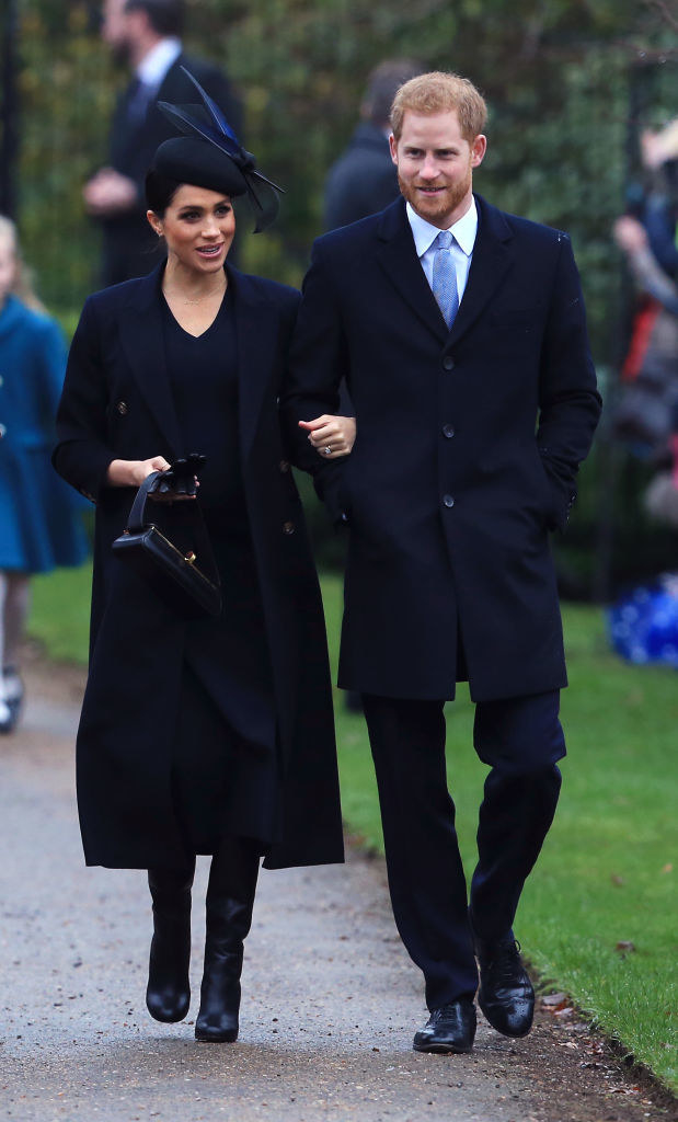 Meghan and Harry are wearing tailored clothes in all black and Meghan wears a hat