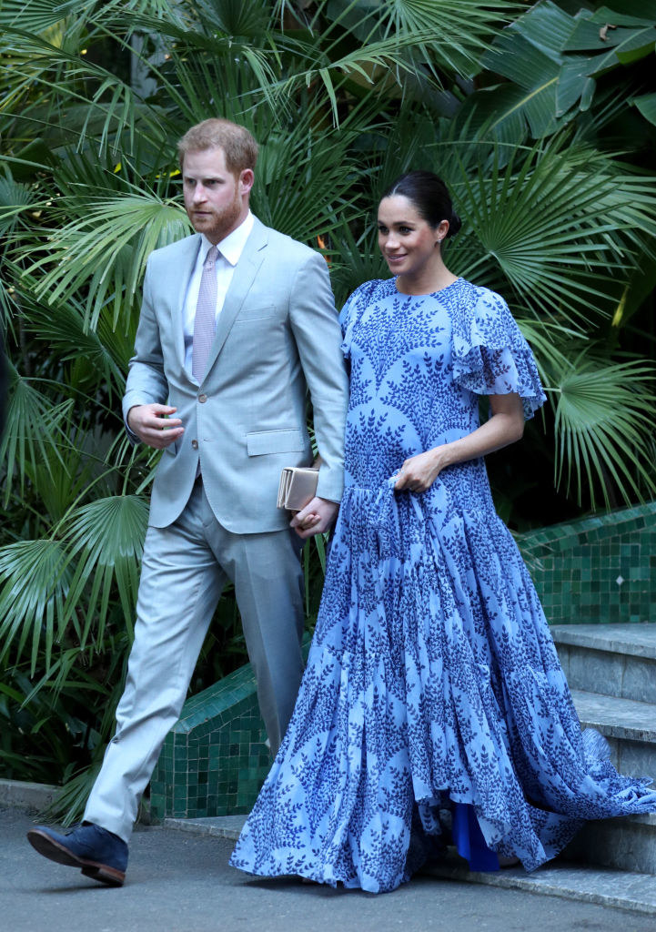 Meghan holds hands with Harry wearing a flowy floor-length dress