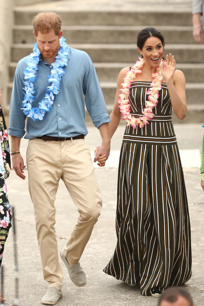 Meghan wears a long striped dress while Harry wears khakis and a button-down shirt