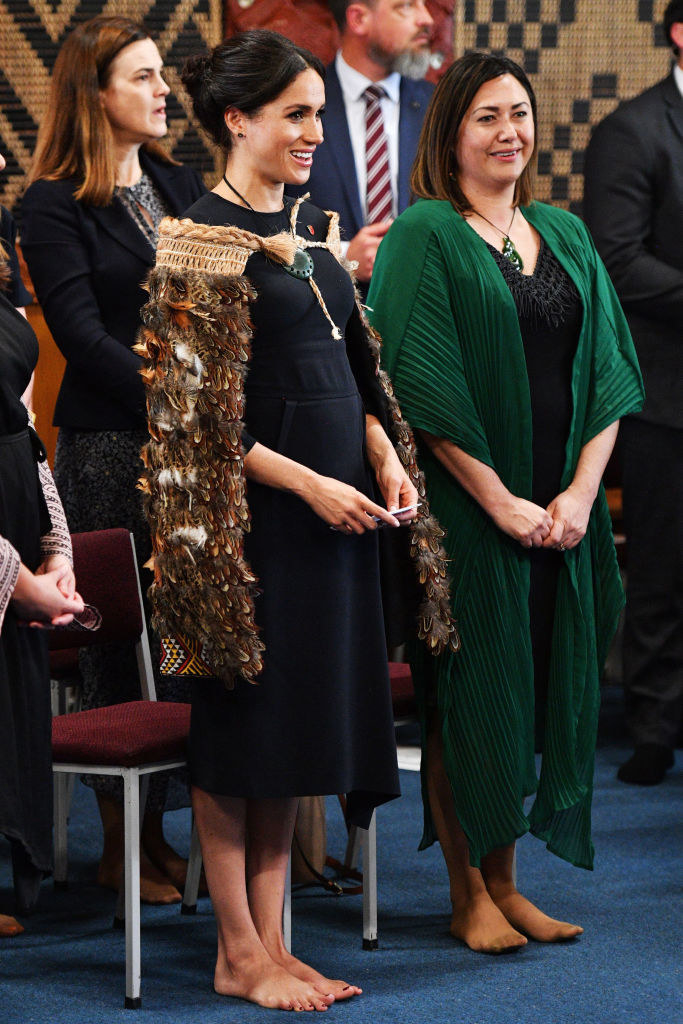 Meghan stands barefoot during a ceremonial event