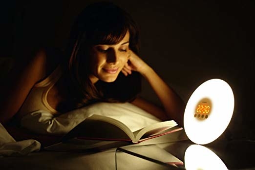 a model reading near the sunlight alarm clock in a bedroom