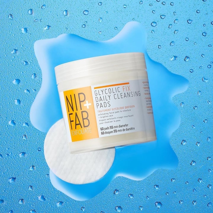 the jar of cleansing pads next to one of the pads against a blue background