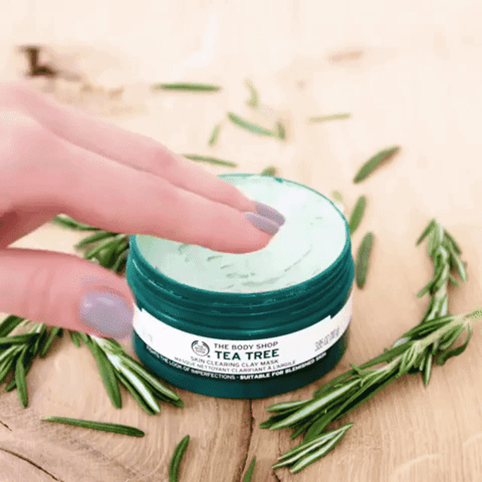 A gif of a hand dipping finger into the jar of The Body Shop Tea Tree Skin Clearing Clay Face Mask