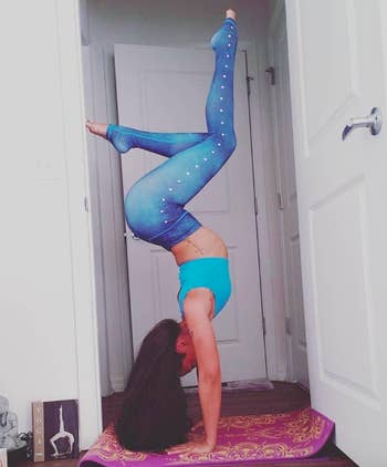 Reviewer wears same leggings in a blue shade while practicing a yoga headstand