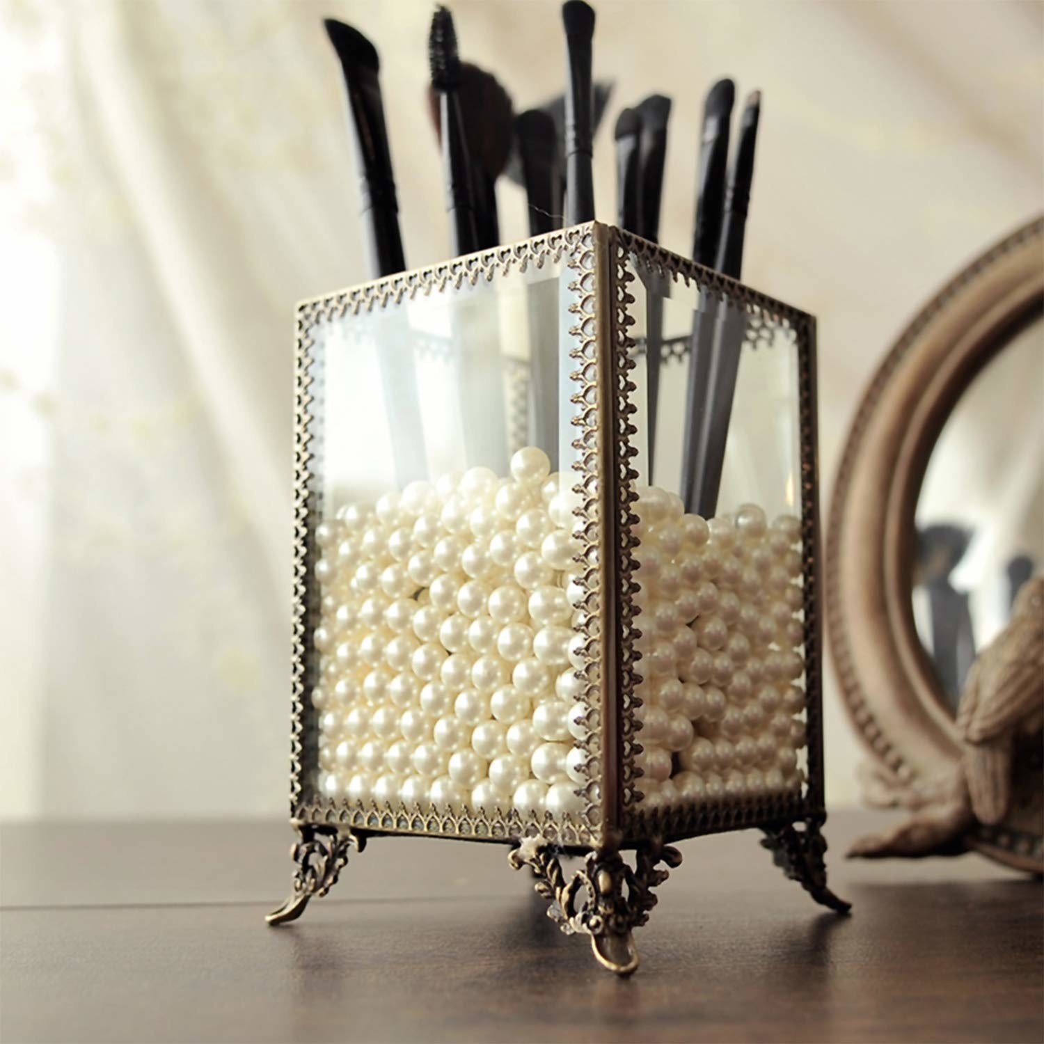 brass and glass container with pearls and makeup brushes 