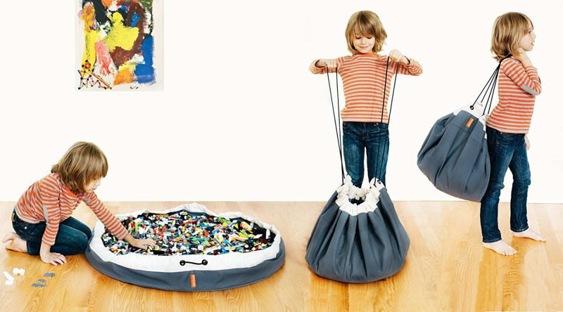 child model playing with circular, open bag full of legos, then pulling the drawstrings, then carrying the bag on their back