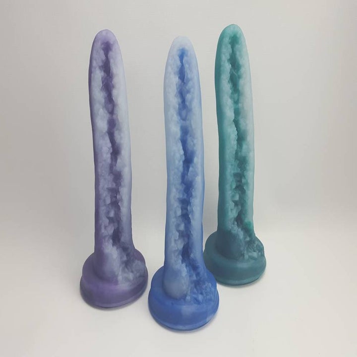 three dildos that look like split open geodes in purple, blue, and green