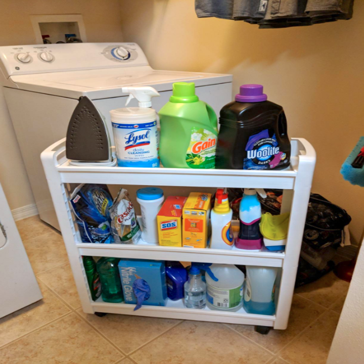 cart pulled out, revealing three shelves packed full with cleaning and laundry products