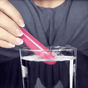 Gif of bullet vibrating in glass of water with lots of splashing 