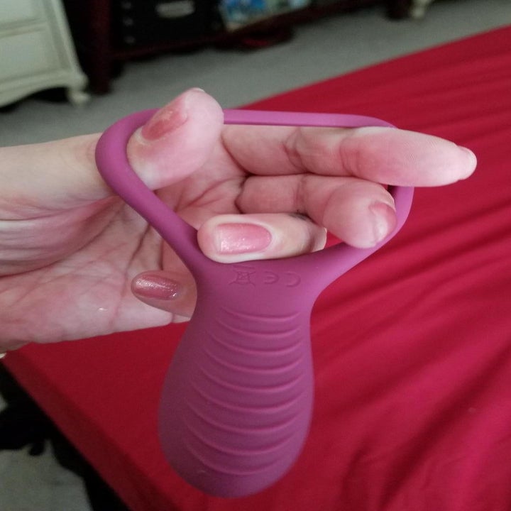 A review photo of a hand stretching out the cock ring