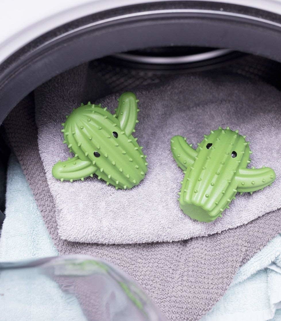 Two small green cacti with black eyes on top of towels in a dryer. 