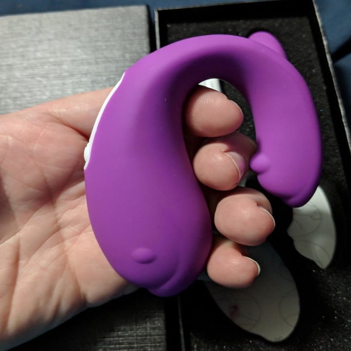 A review photo of a hand holding the curved, two-pronged G spot vibrator 