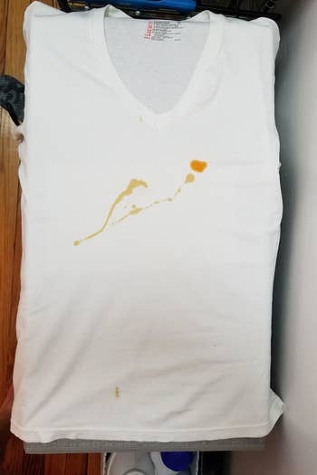 A white T-shirt with a large bright orange food stain