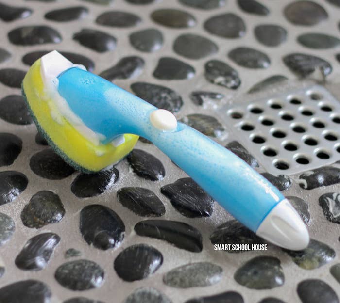 A dishwand filled with blue soap on the floor of the blogger&#x27;s shower