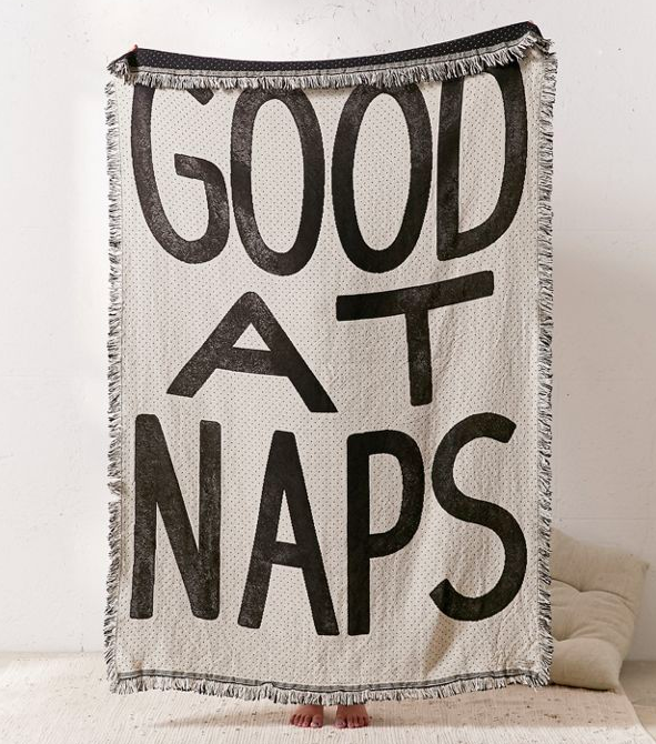 A model holding up a blanket that says &quot;Good At Naps&quot;