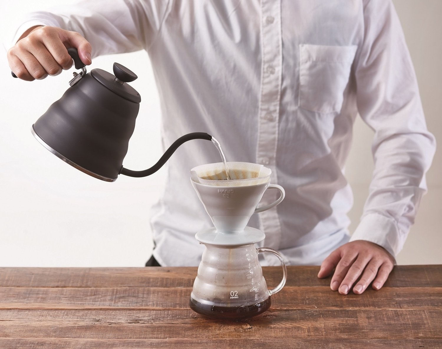 Matte black gooseneck kettle being used for pour over 