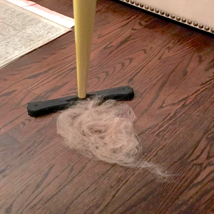 A reviewers pile of hair they extracted from their carpet, and the yellow-handled broom