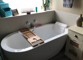 a reviewer photo of the bamboo shelf stretched across a bath tub